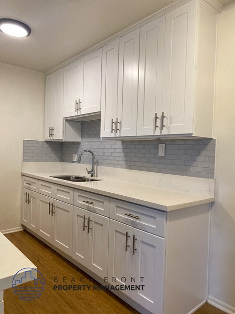 a white kitchen with white cabinets and a sink